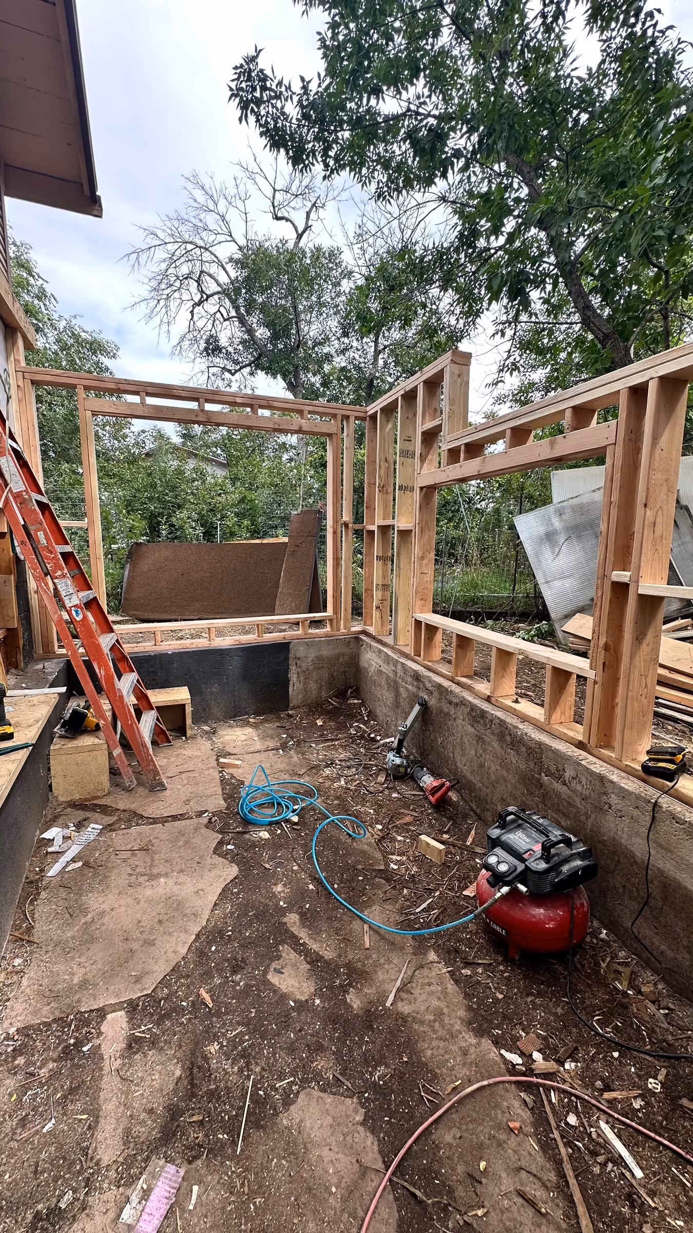 Early addition framing rising from the existing concrete foundation above the excavated work area